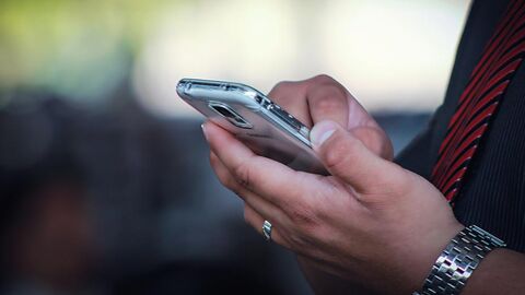 Mann tippt auf seinem Mobiltelefon.